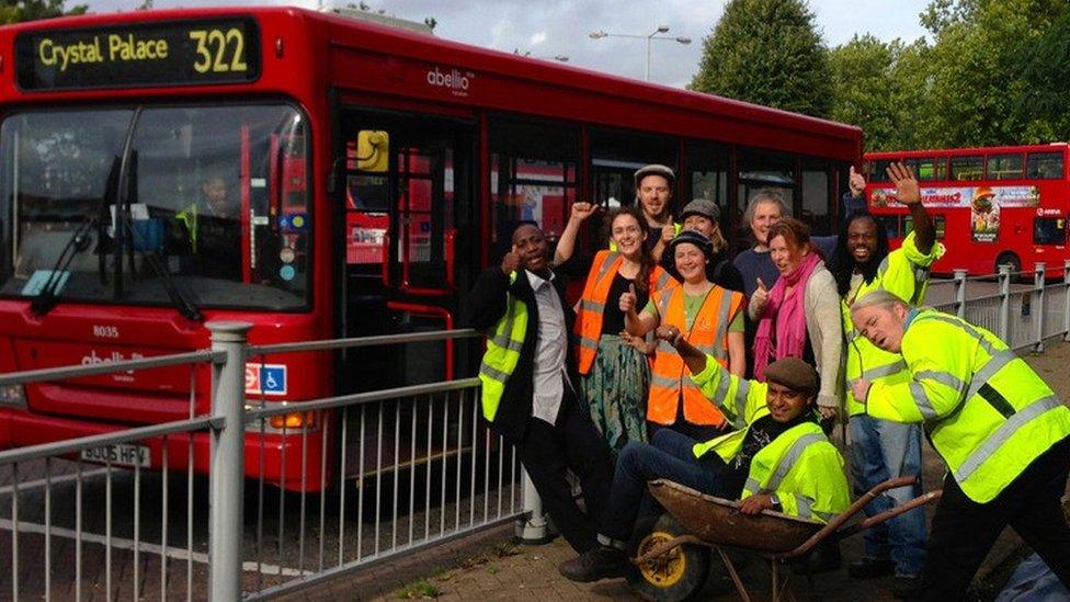 People in wheelbarrow by bus