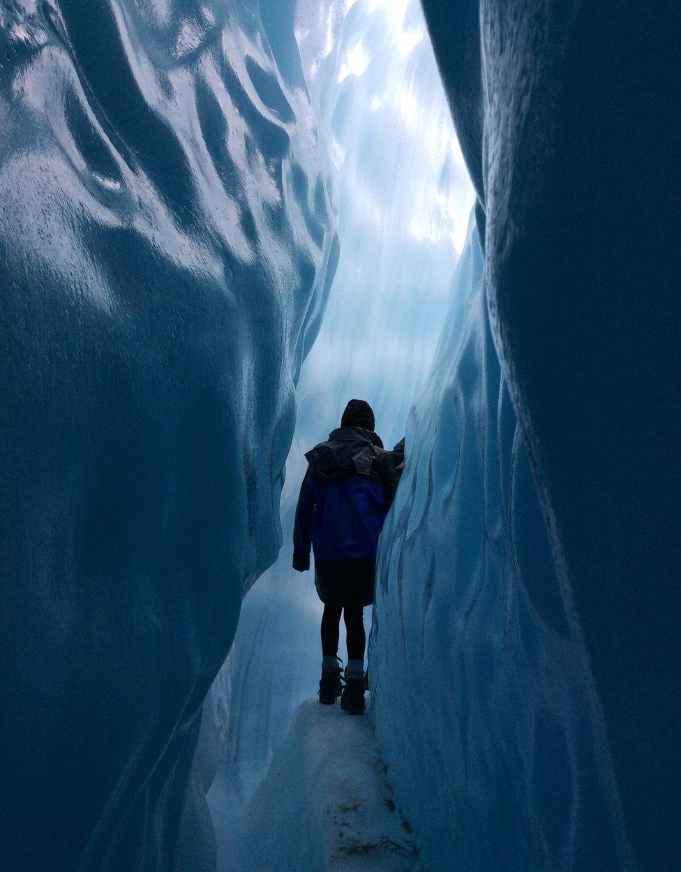 A girl walks through a glacier