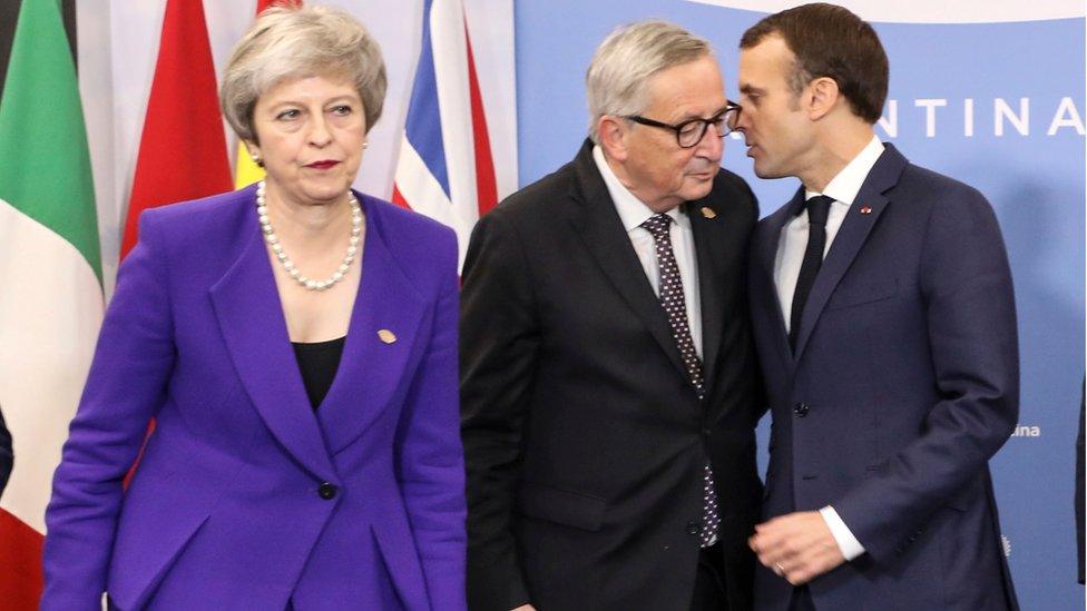 French President Emmanuel Macron (R) speaks with the President of the European Commission Jean-Claude Juncker (C) next to British Prime Minister Theresa May