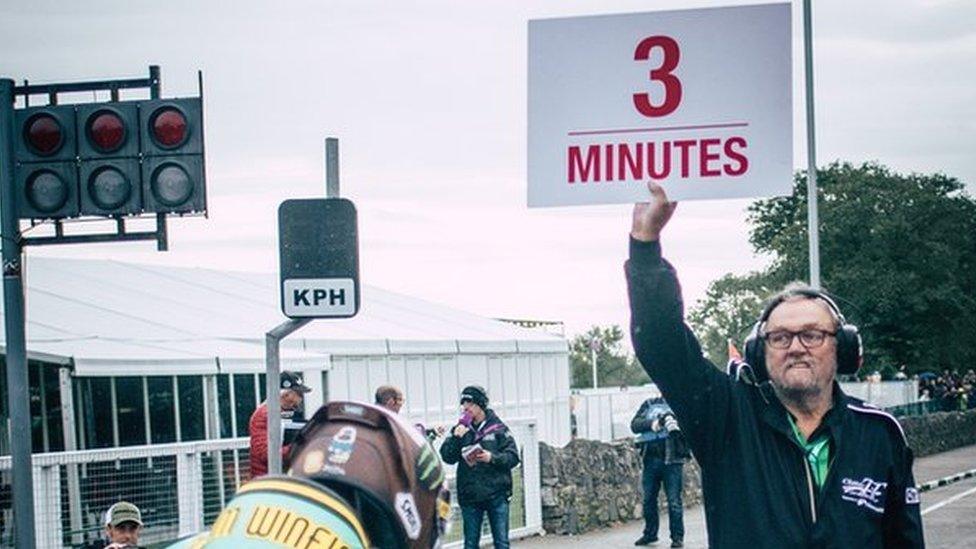 An official signalling three minutes to the start of a qualifying session