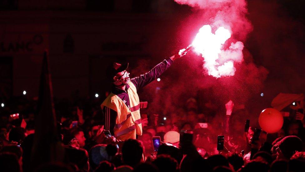 A man wearing a yellow vest lights up a flare on the Champs-Elysees, Paris, 31 December 2018