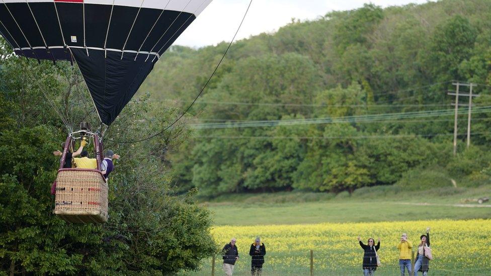 People waving at a hot air balloon taking off at the festival