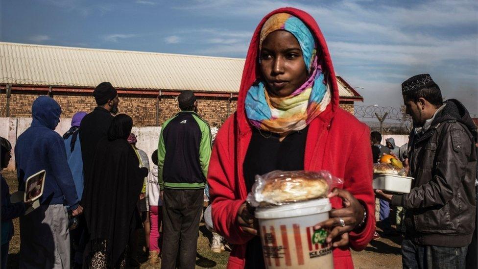 A Muslim woman receives food before breaking the fast for Ramadan in Lenasia, on the outskirts of Johannesburg, on June 26, 2016