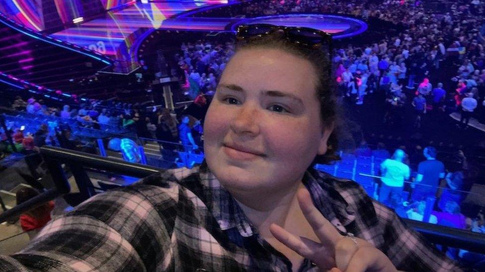 Helen Groothuis smiling for a selfie at the Eurovision semi-final in Liverpool with the stage behind her