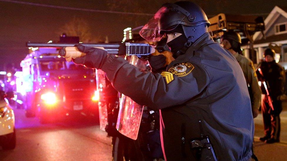 A police officer points a shotgun at protestors during a demonstration in Ferguson, Missouri.