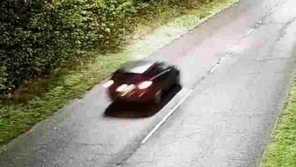 A small black car on a stretch of road.