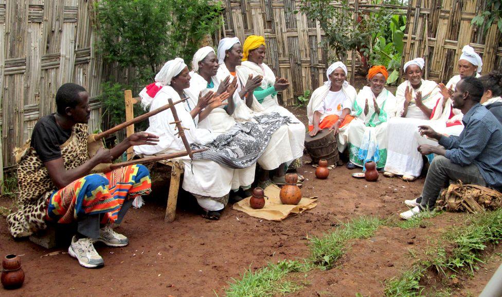 Women sitting in a semi-circle singing