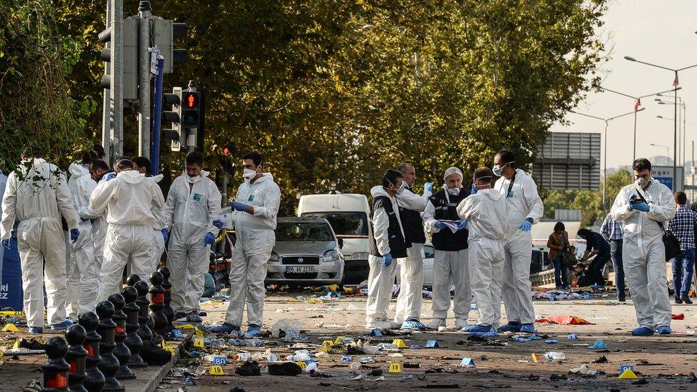 Police and security forces inspect the site of the blasts