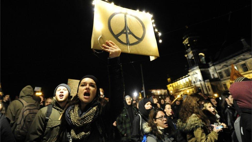 A protester against the Pegida movement holds the "pray for Paris " logo in Dresden