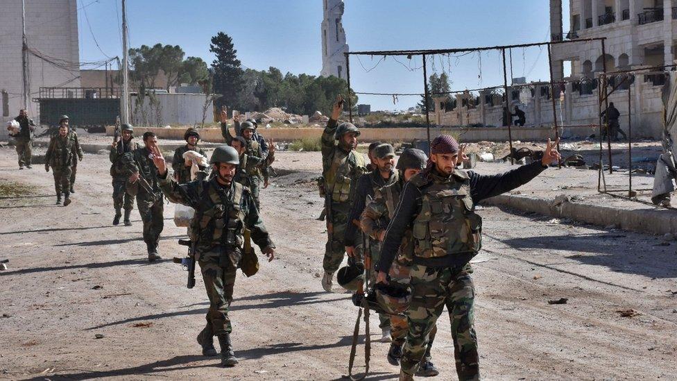 Syrian pro-government fighters gesture as they walk down a road in the Hamdaniya area in eastern Aleppo on 4 November 2016