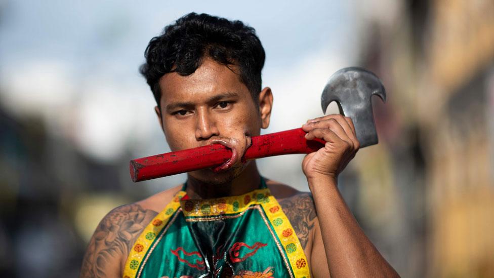 Performer with an axe pierced through his cheek