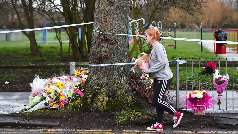 A woman laying flowers by the park