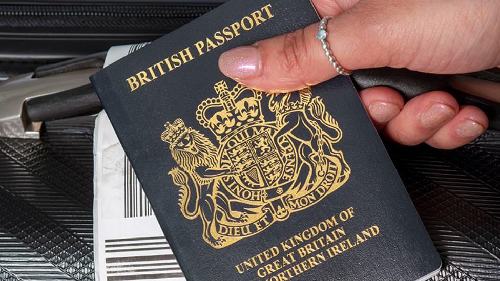 Woman holding a passport by her suitcase