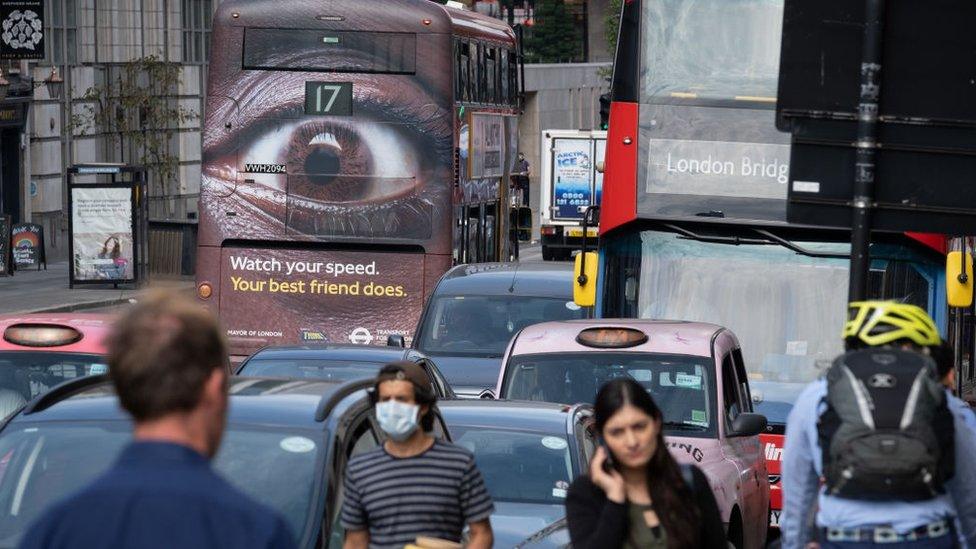 Pedestrians and busy traffic on the Farringdon Road in the City of London with a London bus carrying an ad about speeding in the capital, on 16th September 2020