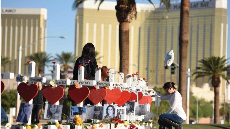 A woman prays near the 58 crosses for the victims of the Las Vegas shooting just south of the Mandalay Bay hotel.