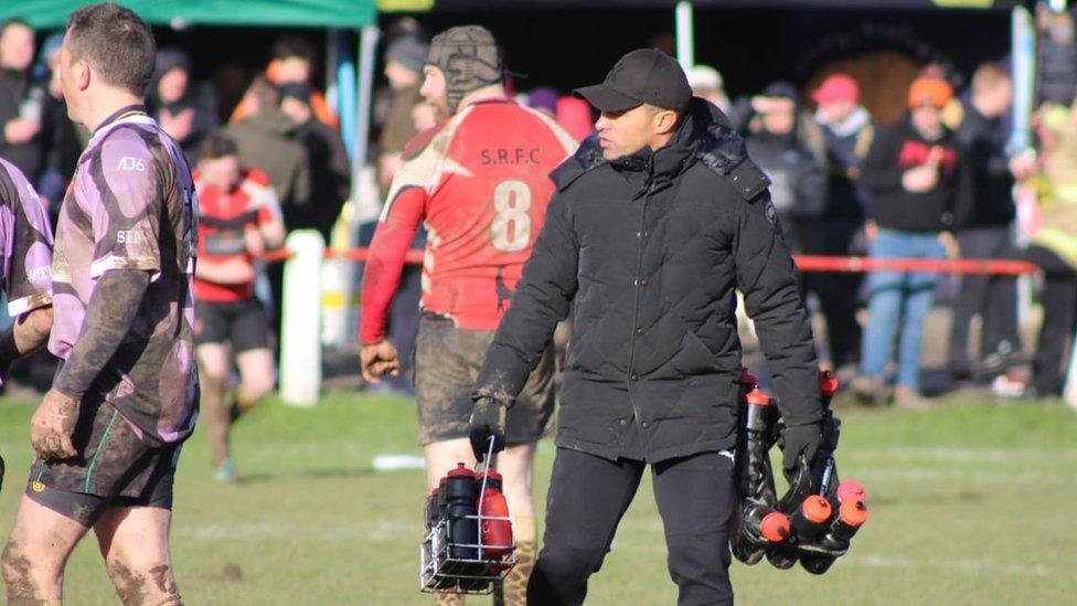 Jason Robinson carrying two crates of water bottles