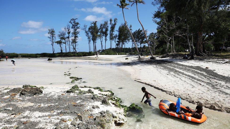 A man tugs a dinghy on a beach in Vanuatu