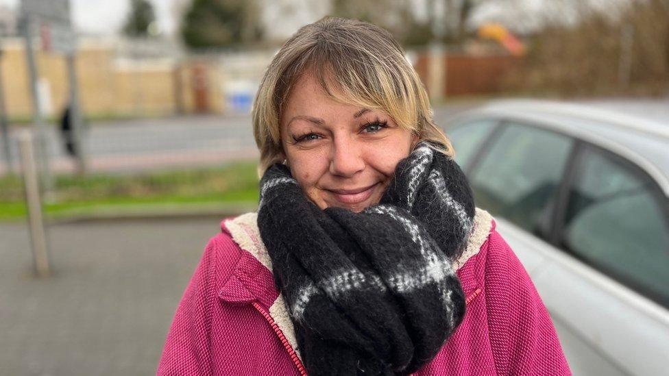 A woman in a pink jacket in a car park