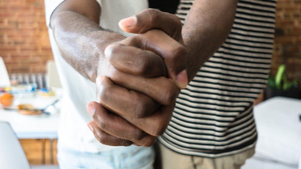 Two men hold hands