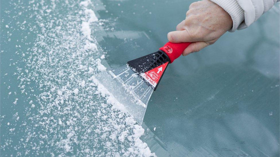 Scraping snow and ice from the car windscreen - stock photo