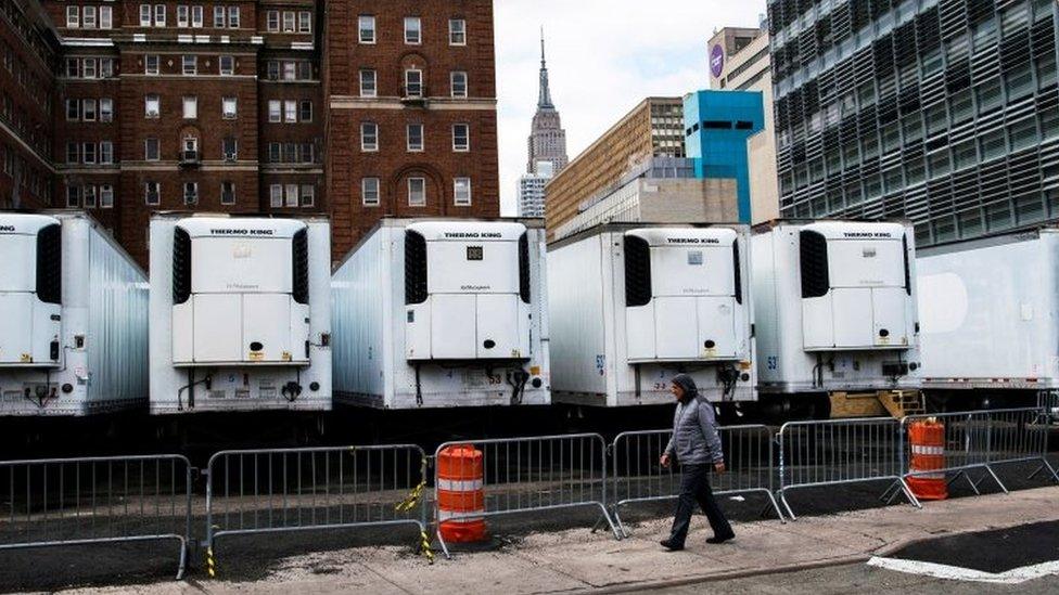 A man walks past refrigeration units used as makeshift morgues in New York City. Photo: 31 March 2020