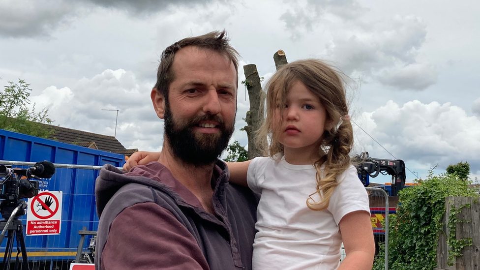 Brad Adcock holding his daughter Esme, three