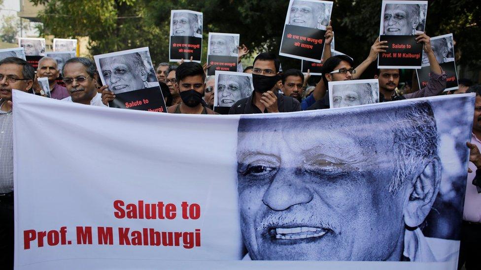 Protesters holding a banner depicting murdered writer Malleshappa Kalburgi