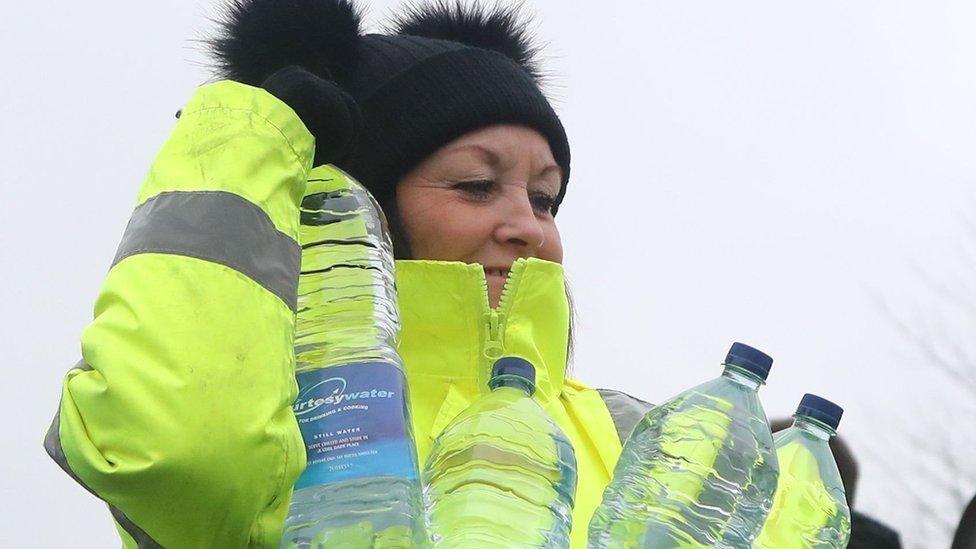 A volunteer from South East Water helps hand out bottles of water in Lenham, Kent