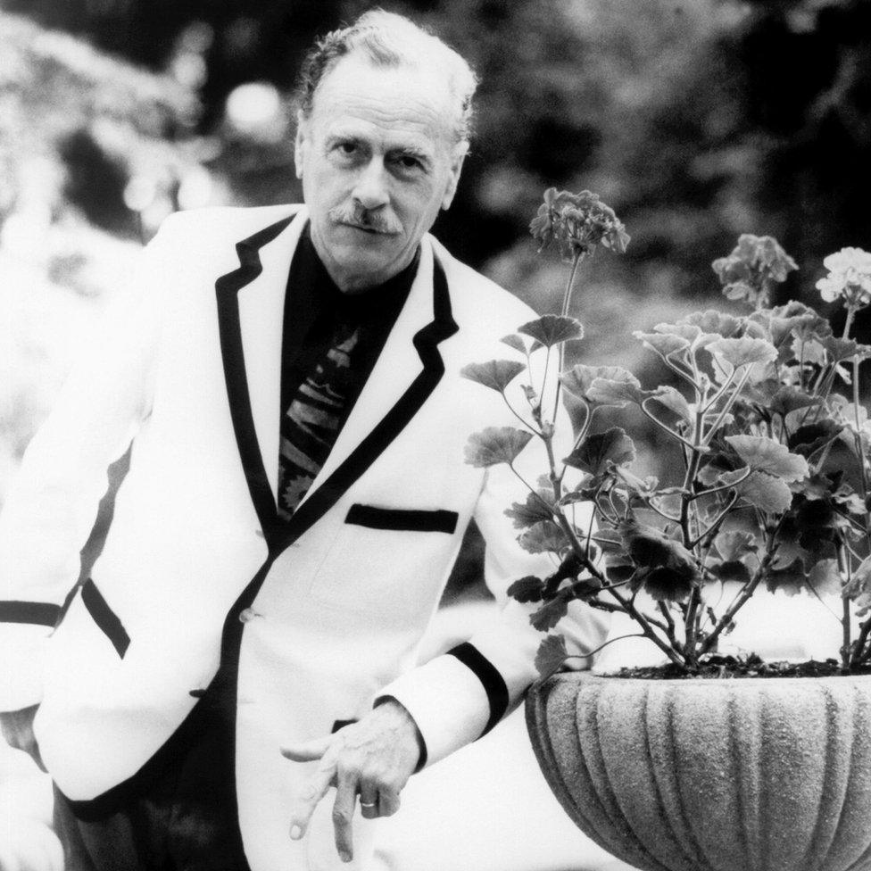 Marshall McLuhan leaning on a stone flower pot