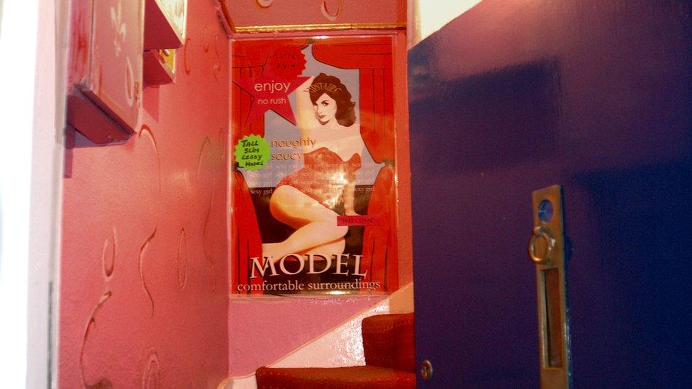 A doorway opening on to stairs showing a poster image for a sex worker