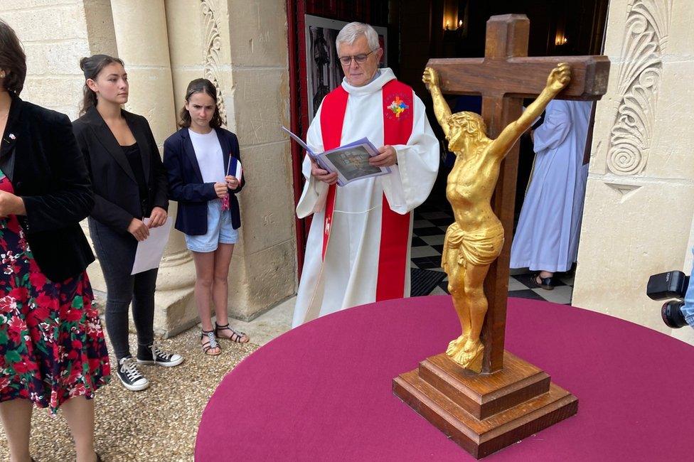 Priest-in-charge Jean-Louis Brunel in background, with crucifix in foreground