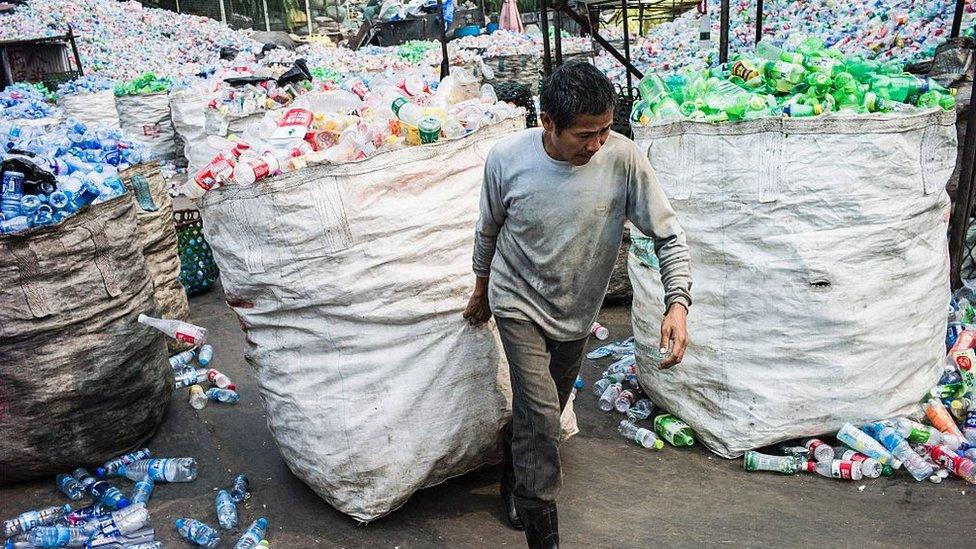 A Chinese worker pulls a bag of plastic bottles being recycled