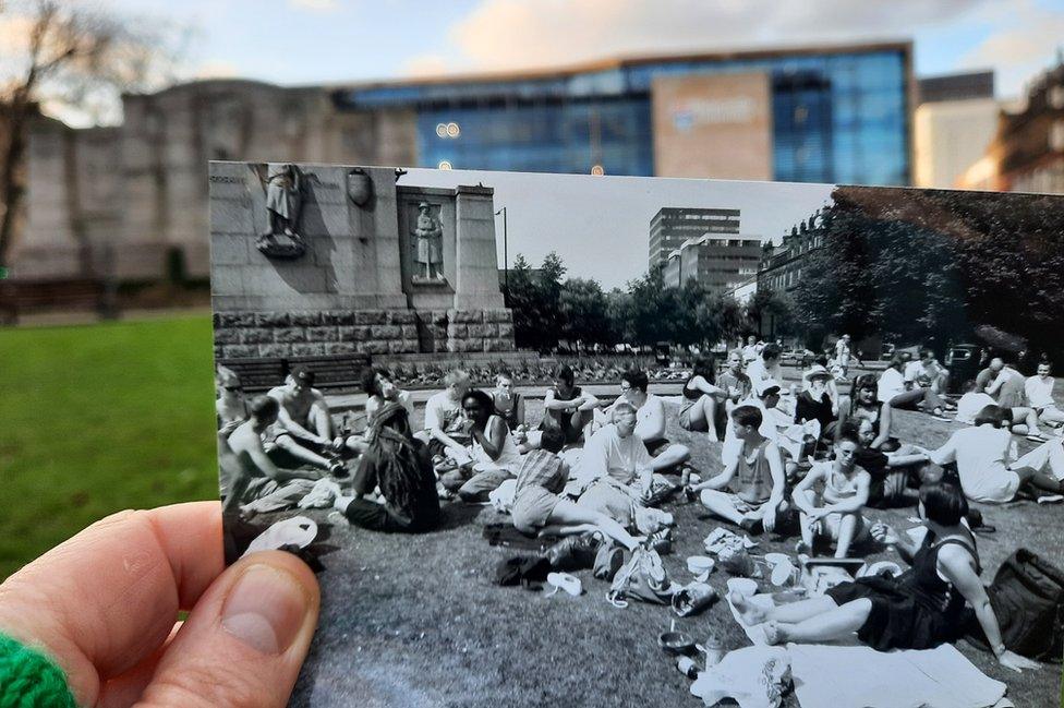 Julie holding a picture of people having a picnic in the centre of Newcastle