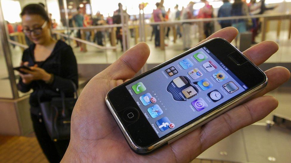 The 1st generation iPhone is held in the palm of a hand outside an Apple store, Hong Kong, 2007