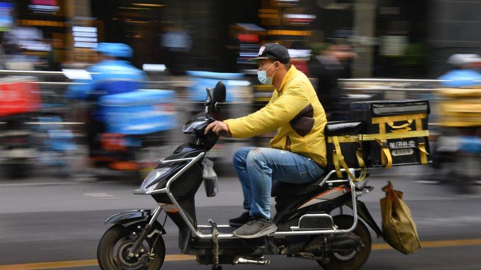 A delivery rider for Meituan, one of China's biggest food delivery firms, heads out to make a food delivery after picking it up at a restaurant in Beijing