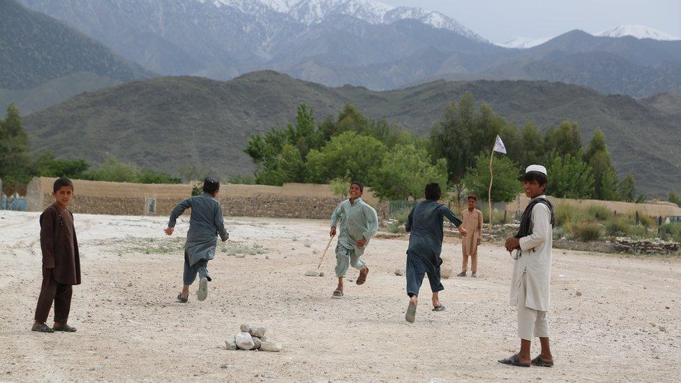 Children play cricket, with a pile of rocks as a stump