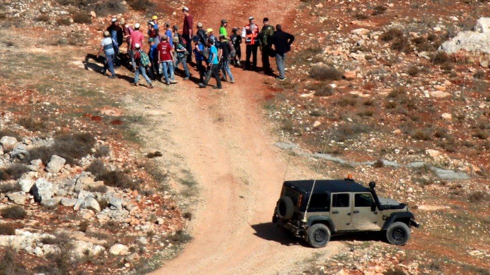 Israeli settlers are led away by Israeli soldiers after an incident near the West Bank village of Qusra (30 November 2017)