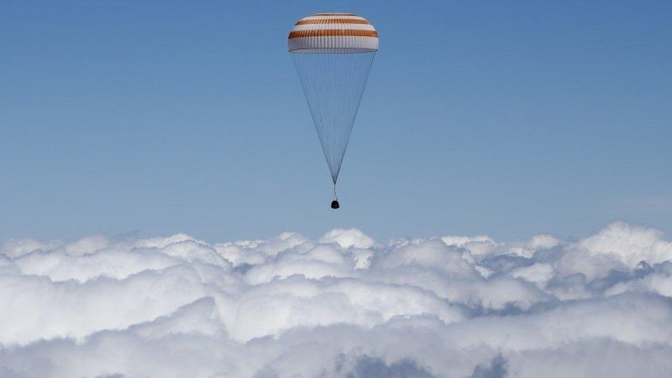 The Soyuz capsule above the clouds beneath its parachute