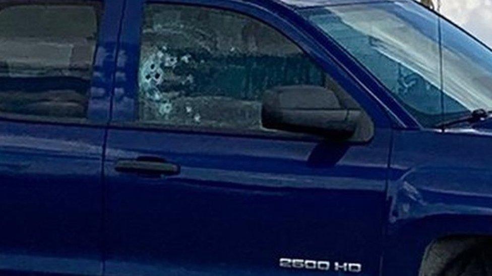 A truck with bullet holes in its side window