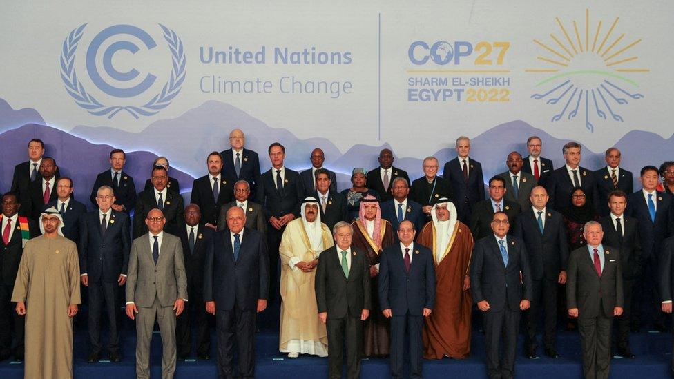 World leaders stand together in front of a UN logo on stage