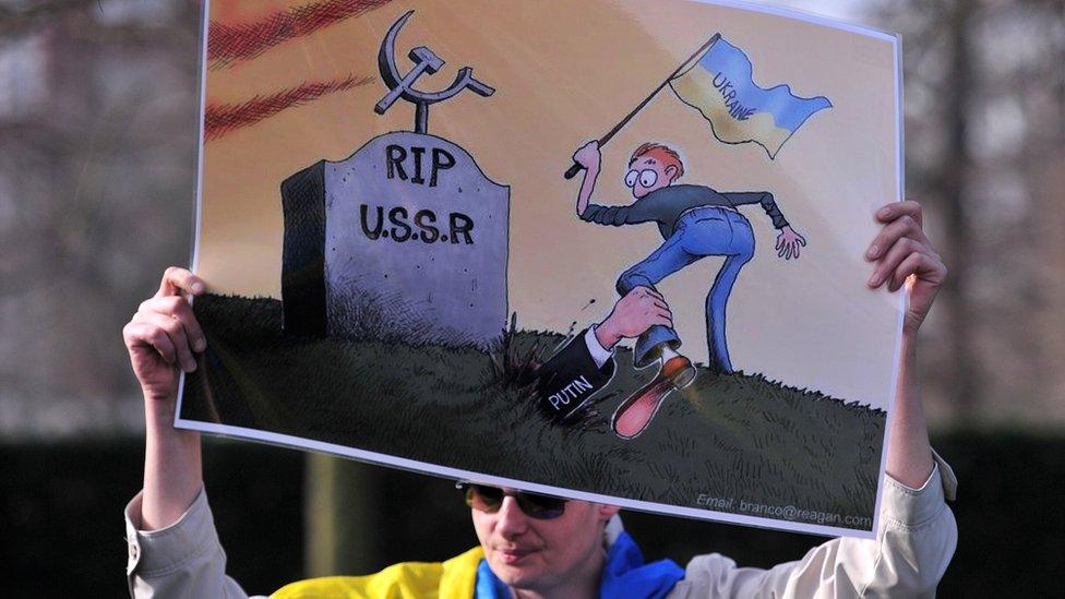 Protestor holding up a cartoon mocking Russia