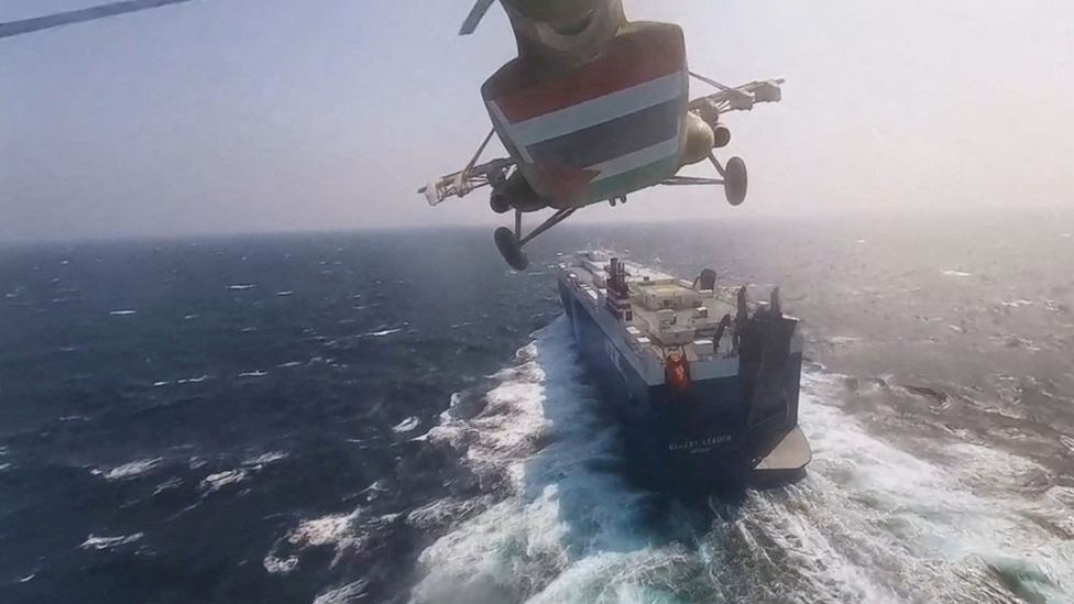 A Houthi military helicopter flies over a cargo ship in the Red Sea