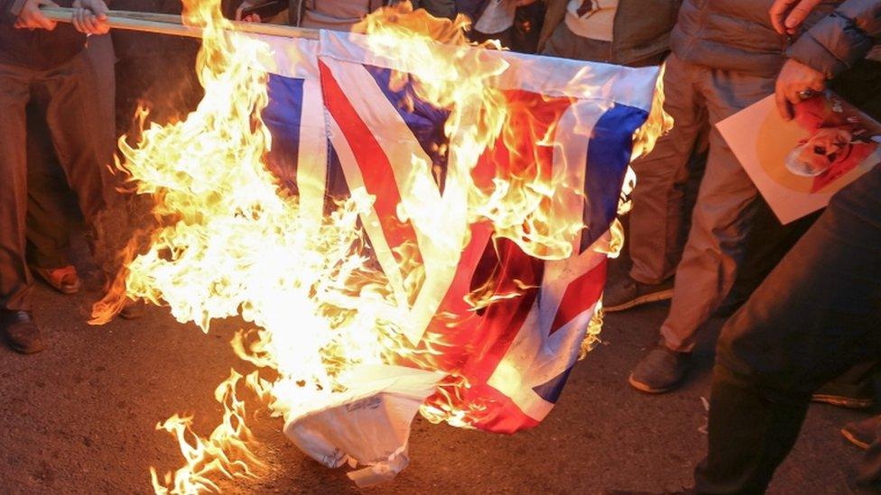 Protesters burn a UK and Israeli flag in Tehran