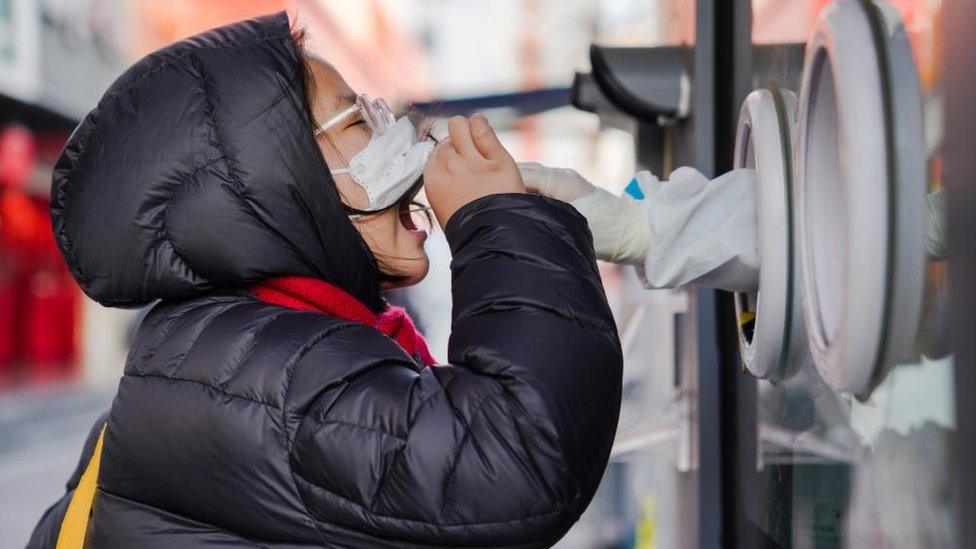 A woman undergoes a swab test to detect COVID-19 at a makeshift testing site in Beijing, China, 04 December 2022