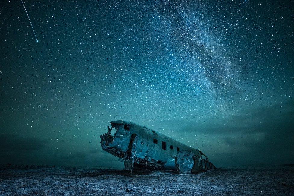 A starlit sky above an abandoned war plane