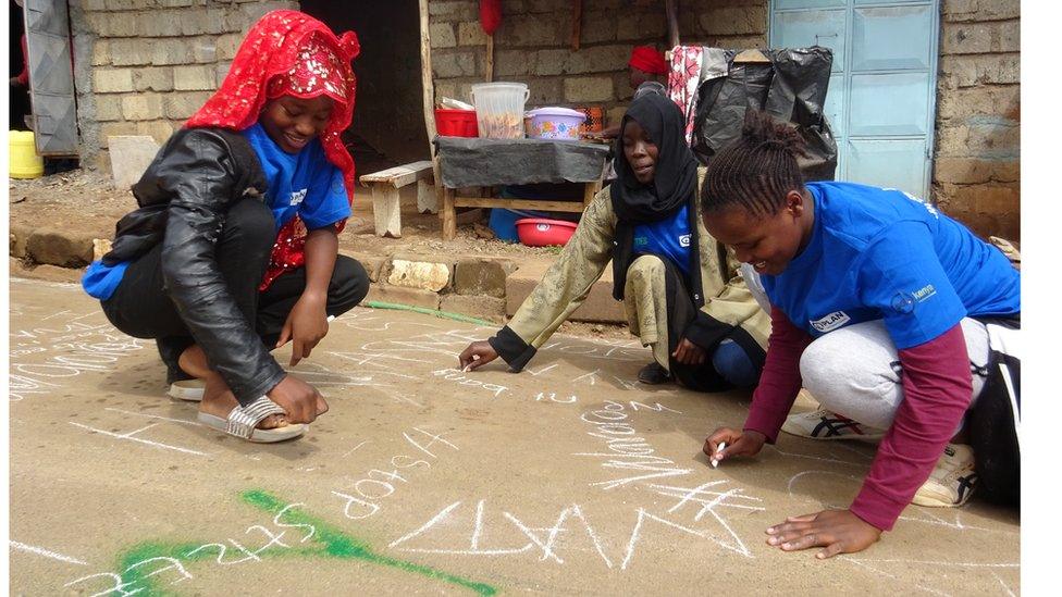 A photo of girls writing their street harassment experiences on roads