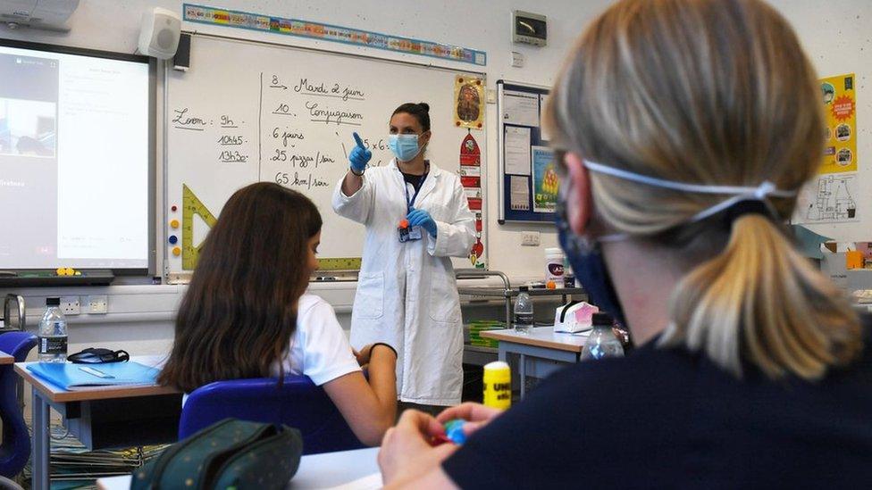 teacher and pupils in classroom wear masks