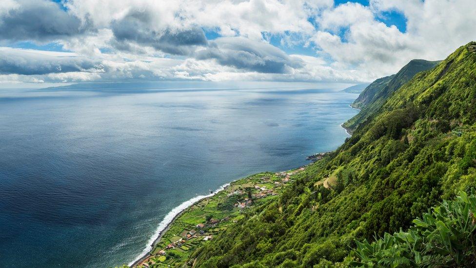 The green coastline of Sao Jorge Island on a calm day.