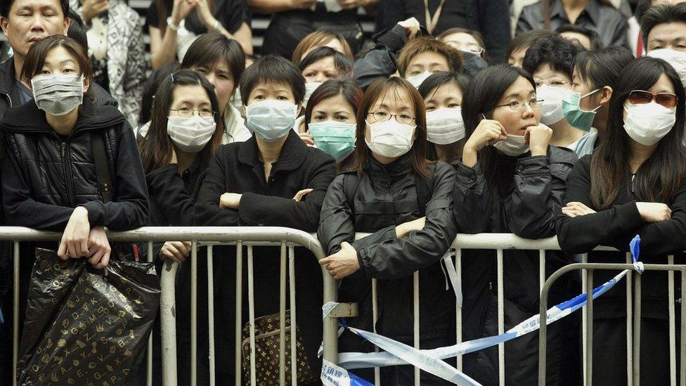 Fans wearing face masks to protect against the pneumonia virus SARS line up to watch the funeral service for Hong Kong actor and singer Leslie Cheung in Hong Kong, 08 April 2003.