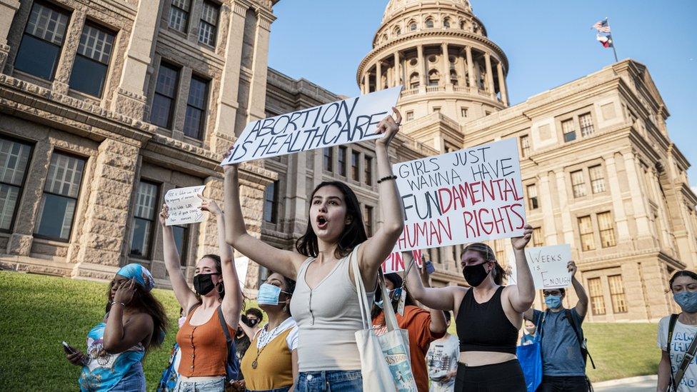 Women march and hold placards outside the Texas State Capitol building